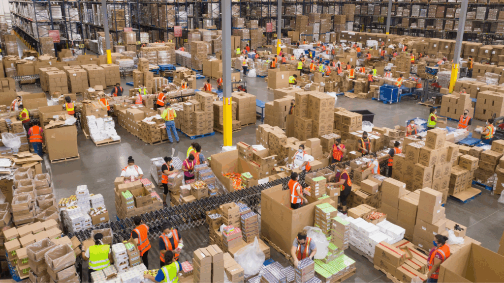 Warehouse workers in high-visibility vests manage boxes and pallets during retail peak season, illustrating the importance of real-time inventory visibility and warehouse analytics for SLA protection.