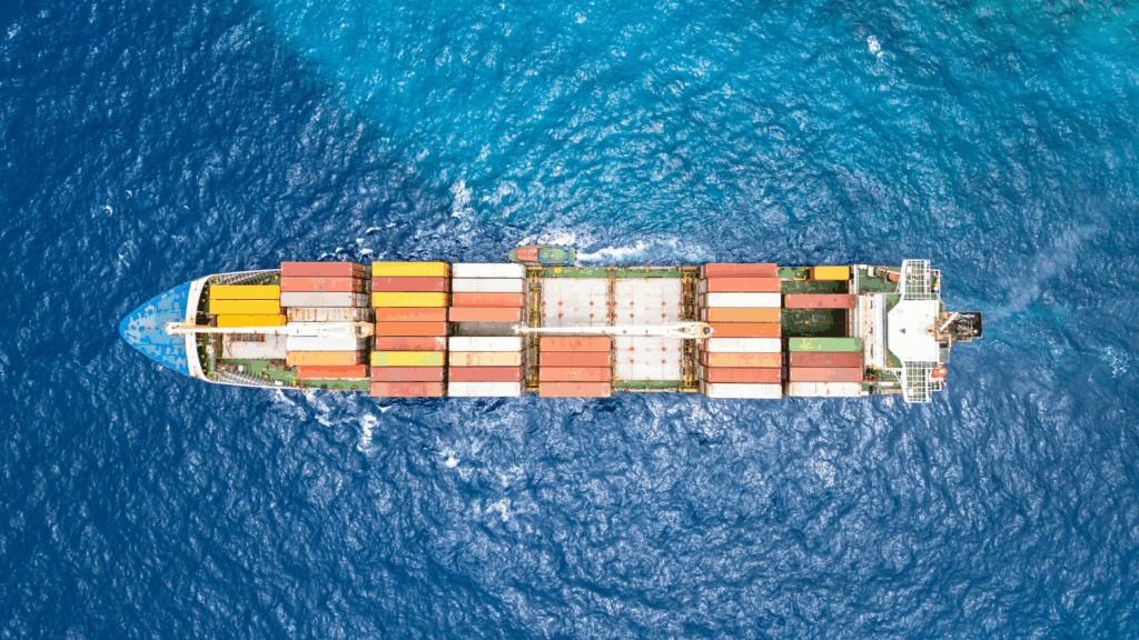 An overhead view of a cargo ship carrying colorful shipping containers across the ocean, illustrating global freight movement and the role of supply chain execution in managing transportation and international logistics.