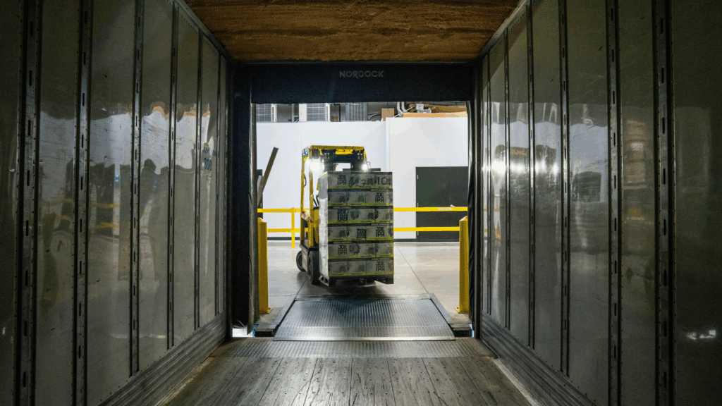 A forklift loading a pallet of goods into a trailer at a warehouse dock, illustrating warehouse operations and the role of supply chain execution in managing inventory movement and efficient order fulfillment.