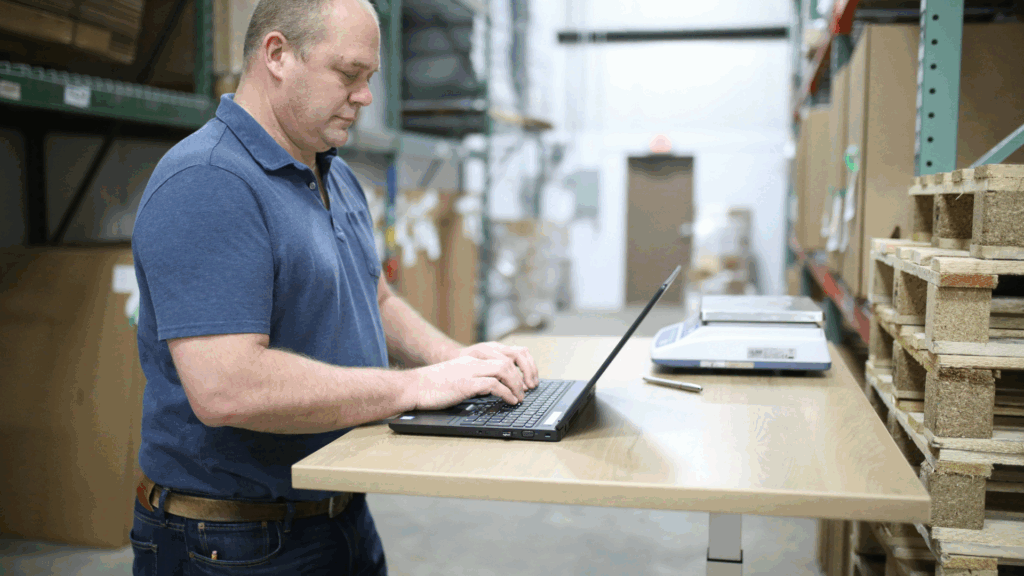 Warehouse supervisor reviewing labor and performance data on a laptop, demonstrating how real time visibility improves decision making through labor management system integration.