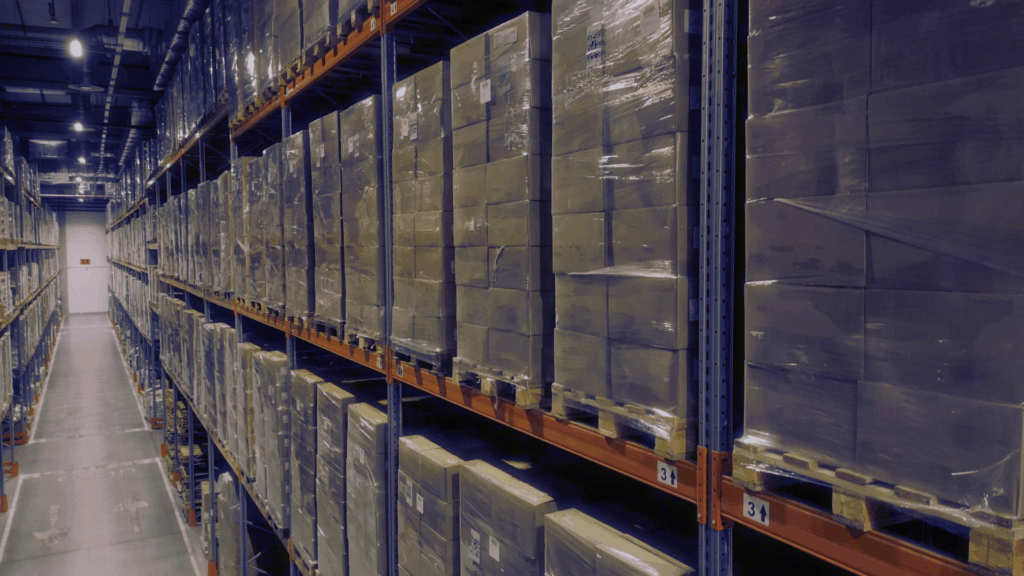 Rows of pallet racks filled with wrapped inventory, illustrating warehouse inventory metrics used to manage carrying cost of inventory.