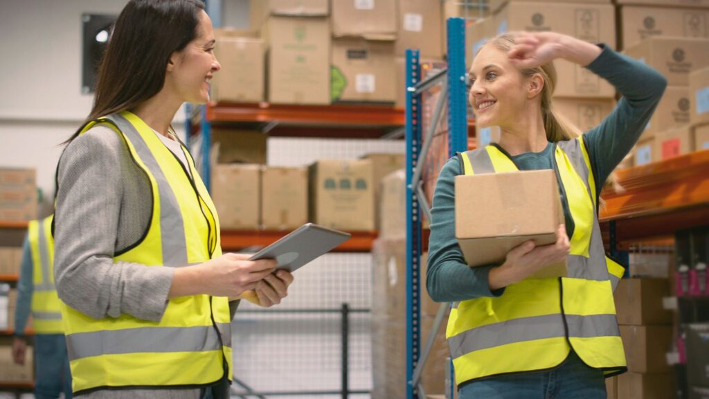 Warehouse supervisors reviewing work on the warehouse floor while discussing inventory and daily operations
