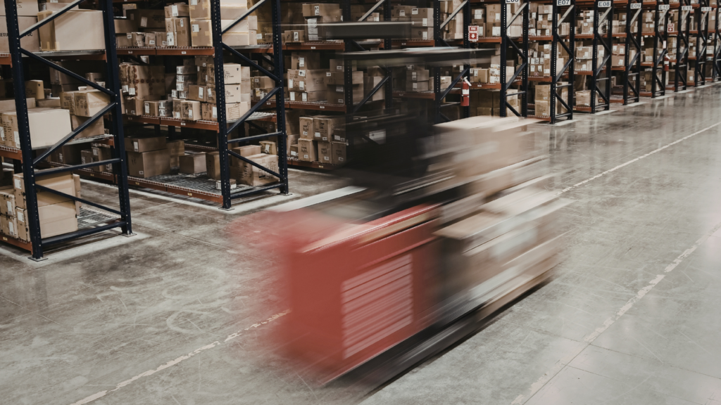 Fast-moving forklift in warehouse aisle illustrating real-time operations and the need for warehouse analytics vs business intelligence tools in supply chain environments
