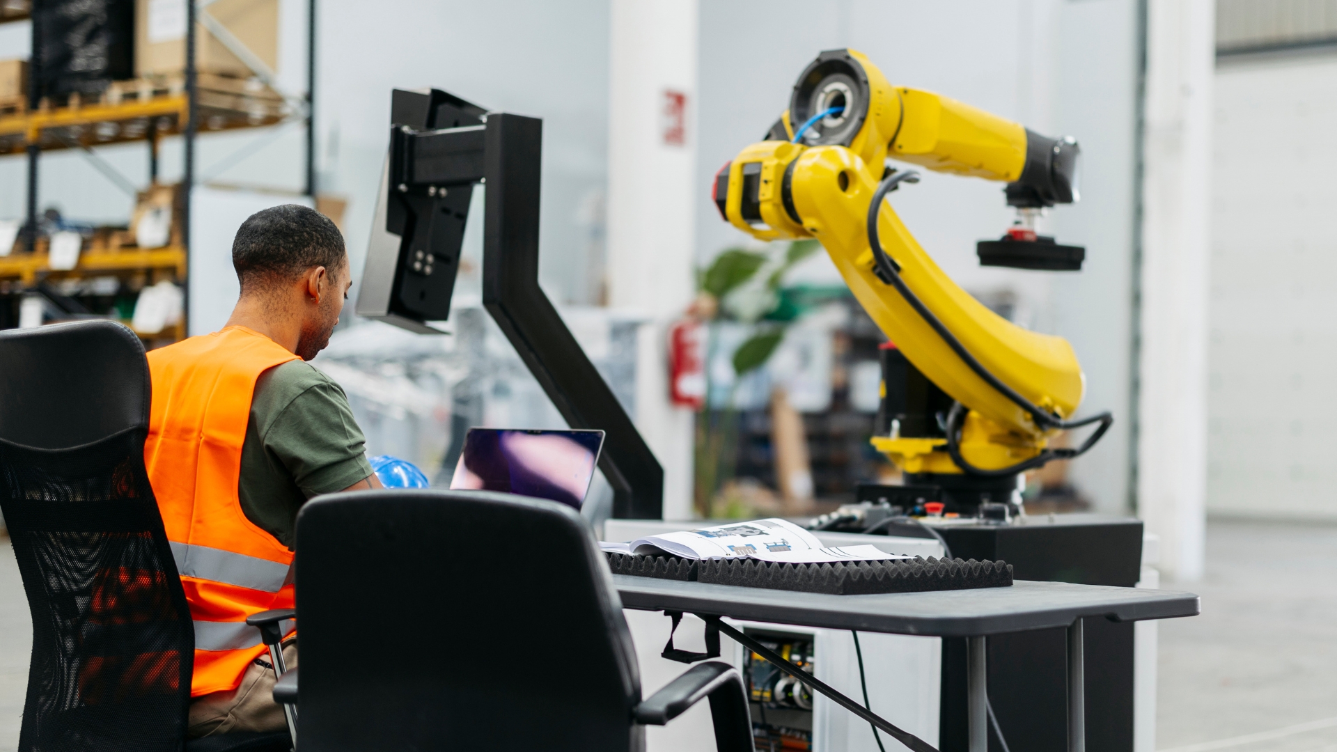 Warehouse operations technician working alongside an industrial robotic arm, illustrating the gap between warehouse automation and real-time labor orchestration