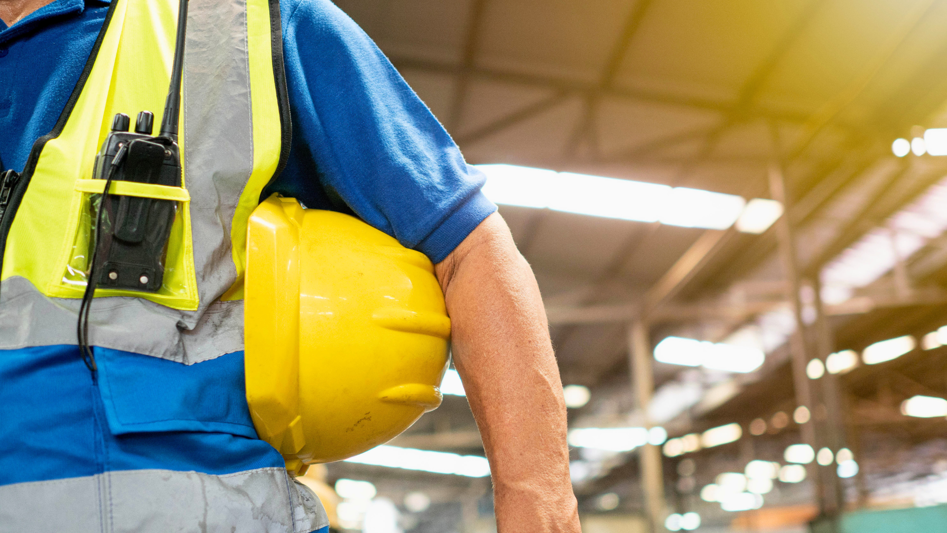 Warehouse associate holding a hard hat and radio, representing frontline labor in a distribution center